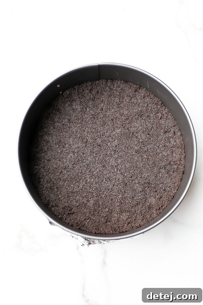 A dark chocolate cookie cheesecake crust on the bottom of a metal pan