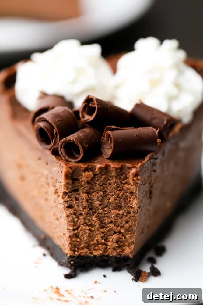 Close up of a slice of chocolate cheesecake on a white plate with a bite taken out of it