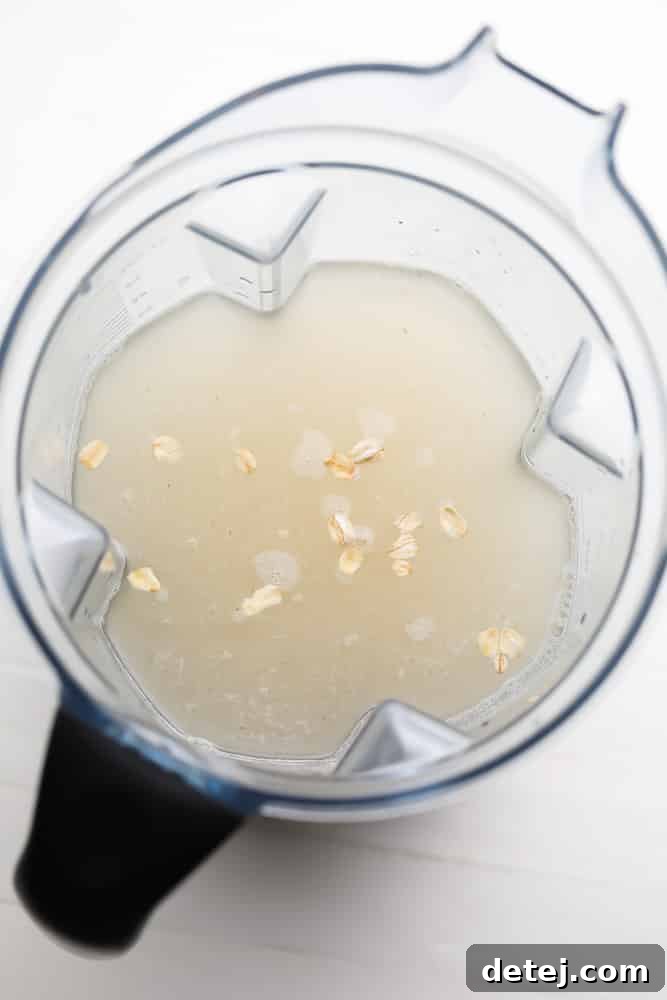 Rolled oats and cold water being added to a blender for making oat milk.