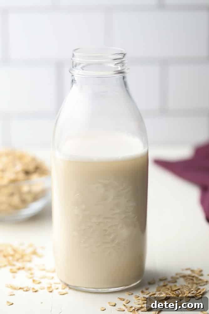 Tall glass jar of homemade oat milk, stored in the refrigerator.