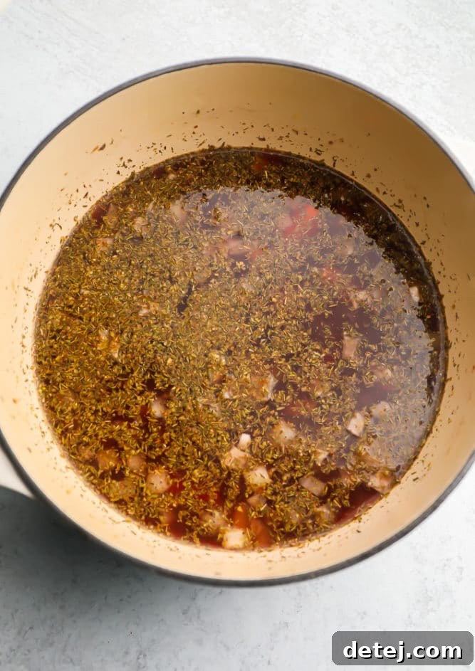 Cooking vegetable broth, vegetables, and herbs in a large pot