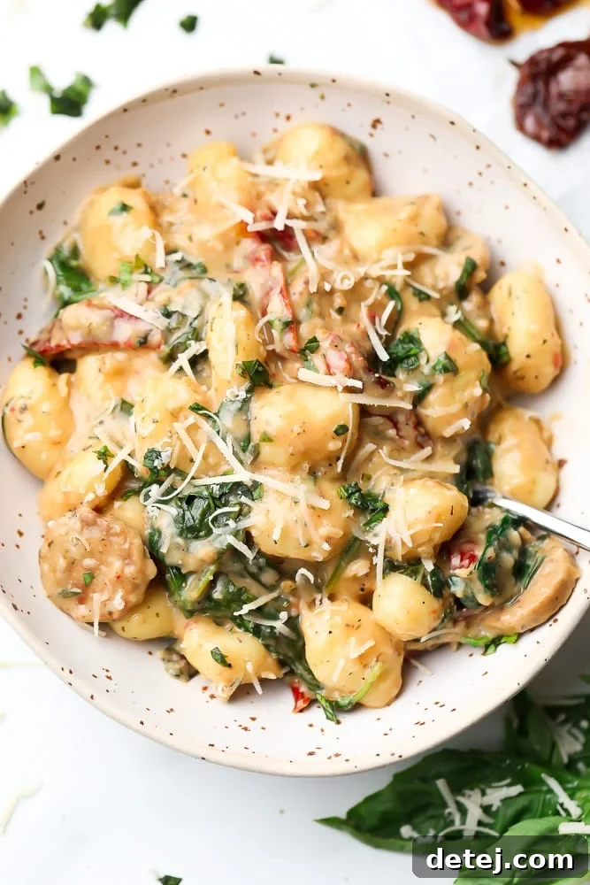 bowl of vegan gnocchi with spinach and sun dried tomatoes in background