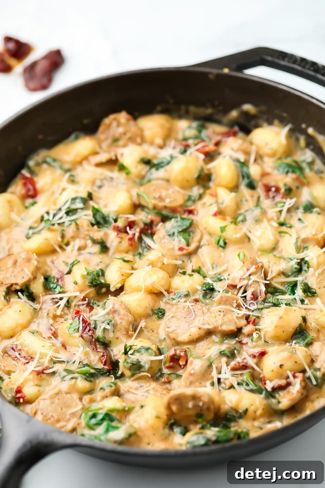 cast iron pan from side with gnocchi and  vegan sausage