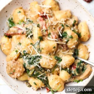 close up square image of pasta in bowl with spinach and tomatoes