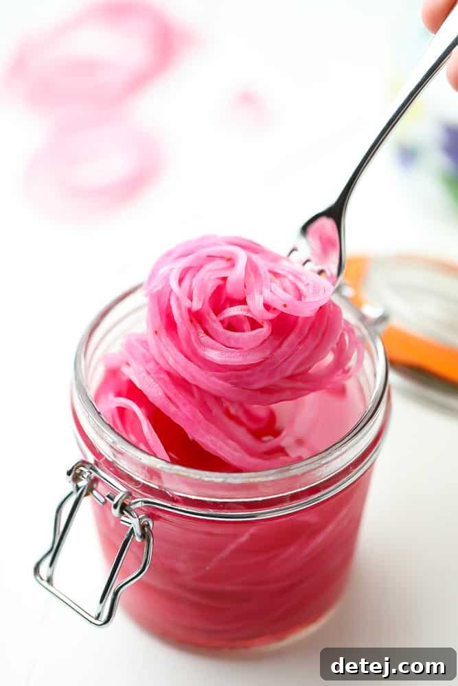 Tangy Ruby Onions 3 scooping pickled red onions out of a jar with a fork