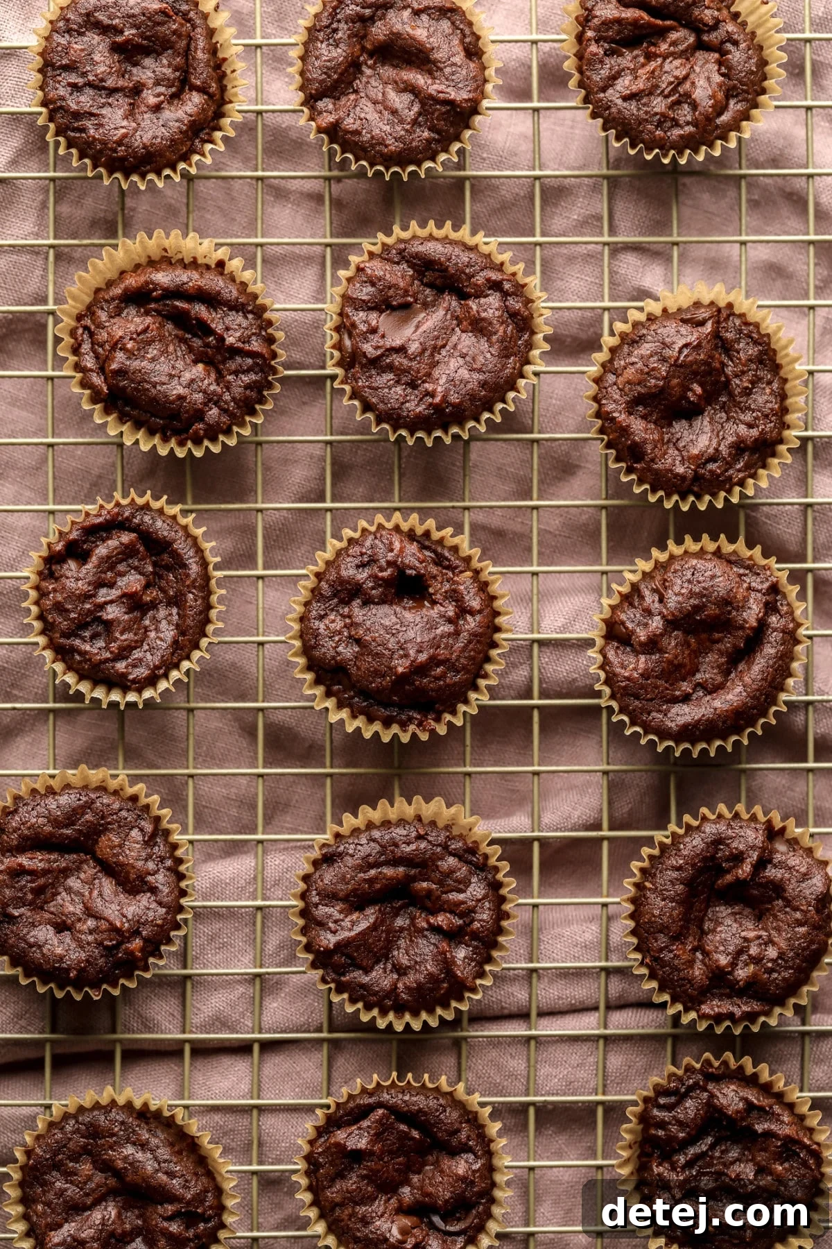 A vibrant pink towel provides a backdrop for a cooling rack, laden with an array of perfectly baked vegan brownie bites.