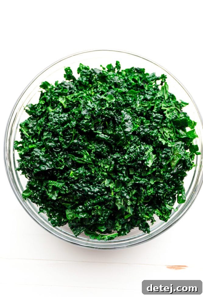 A large bowl filled with vibrant, freshly chopped lacinato kale, ready for dressing.