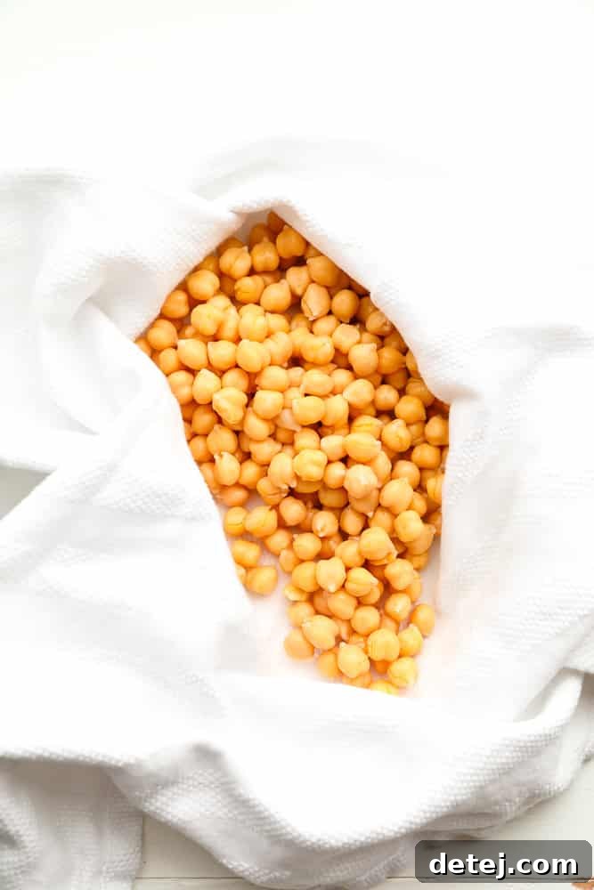 Freshly rinsed and drained chickpeas gently drying on a white dish towel, preparing for their transformation into crispy croutons.