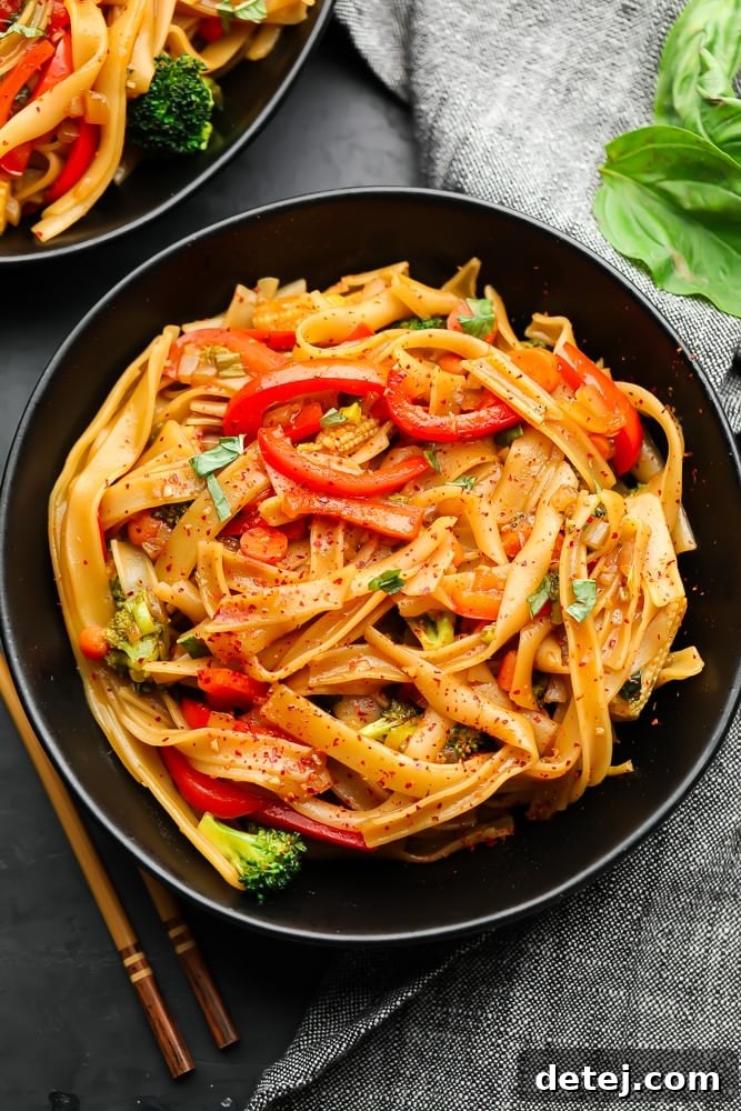 two bowls of vibrant vegan drunken noodles with fresh vegetables