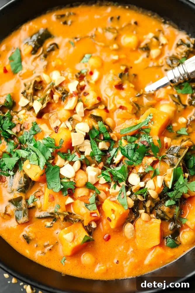 close up of a bowl of orange peanut soup with cilantro and peanuts on top