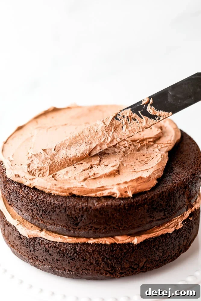 Hands frosting a rich gluten-free vegan chocolate cake with decadent chocolate frosting, creating a smooth, inviting finish.