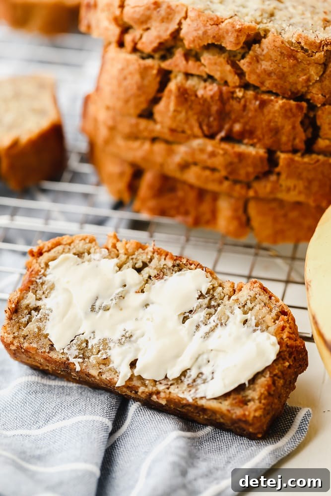 A delectable slice of buttered gluten-free vegan banana bread rests beside a whole loaf, ready to be enjoyed.