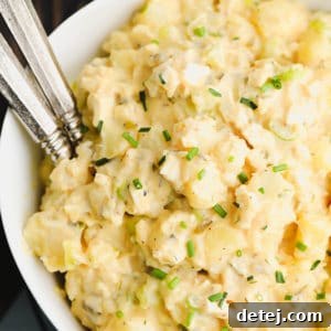 Square image of best vegan potato salad in a bowl, showing its creamy texture and fresh herbs.