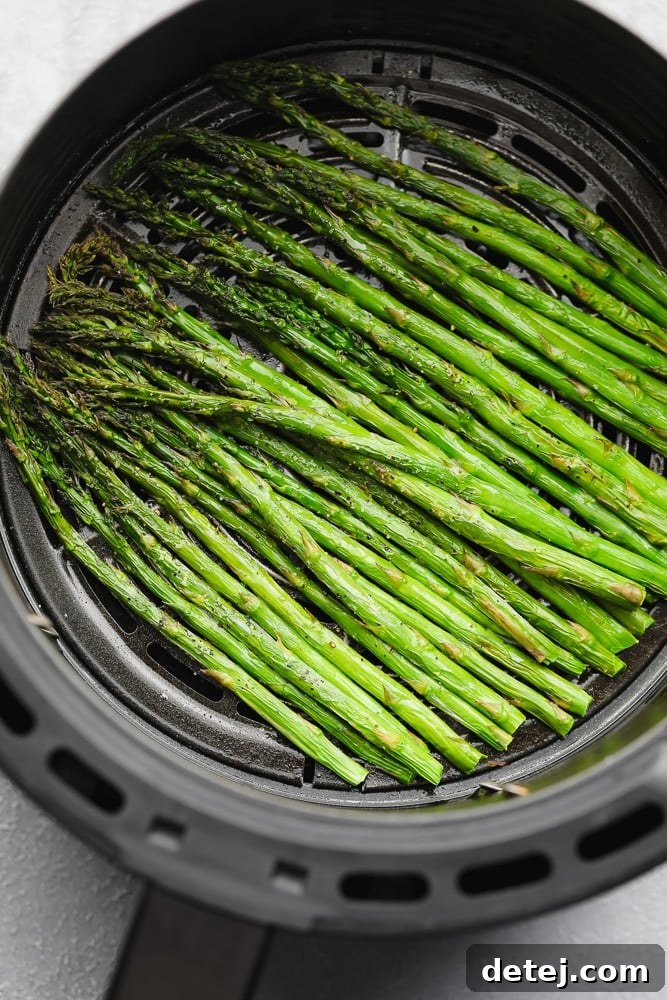 cooked asparagus in an air fryer basket