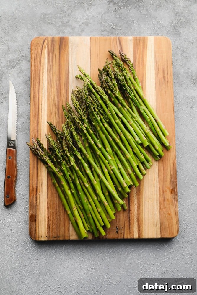raw asparagus on a wood board next to a knife