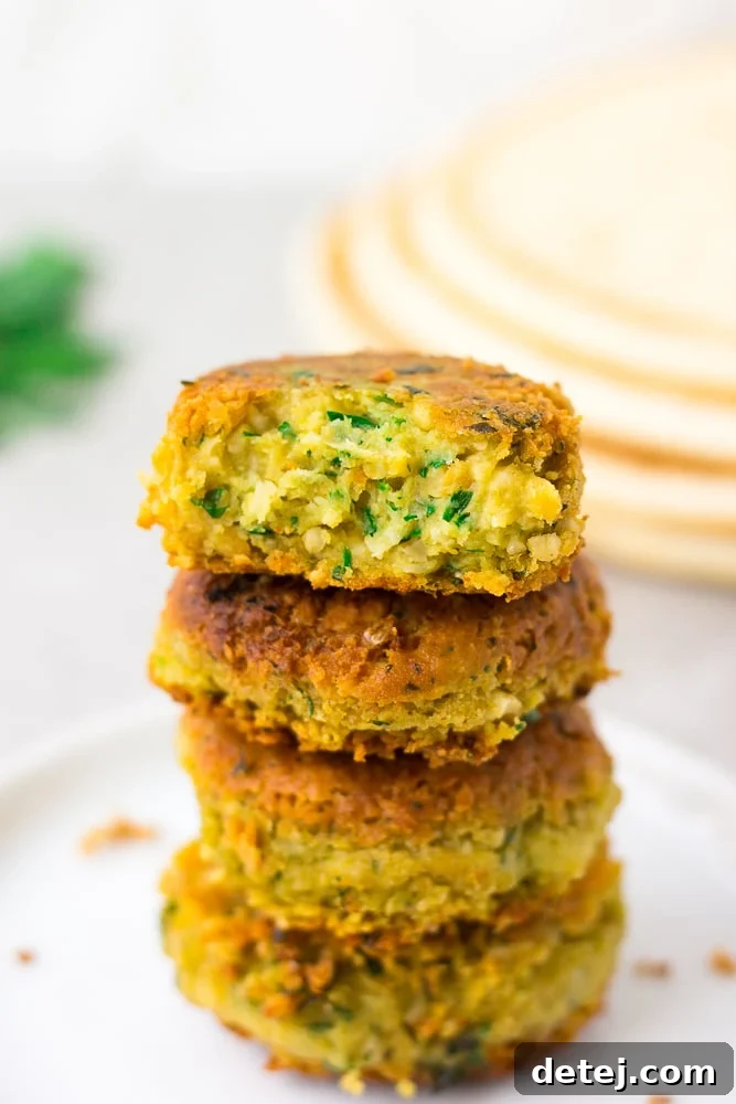 Four golden-brown vegan falafel patties neatly stacked on a rustic surface