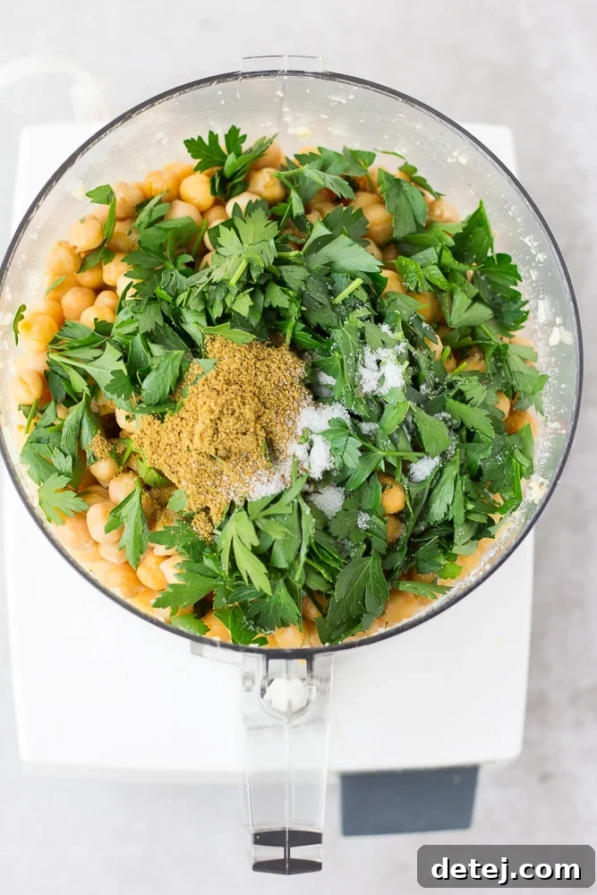 Chickpeas, garlic, parsley, cashews, and spices ready to be pulsed in a food processor for vegan falafel