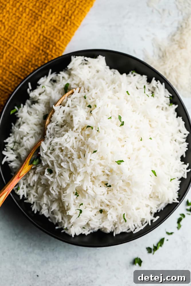 A black bowl filled with perfectly cooked white Basmati rice, with a wooden spoon resting inside, ready to be served. The rice is fluffy and separated.