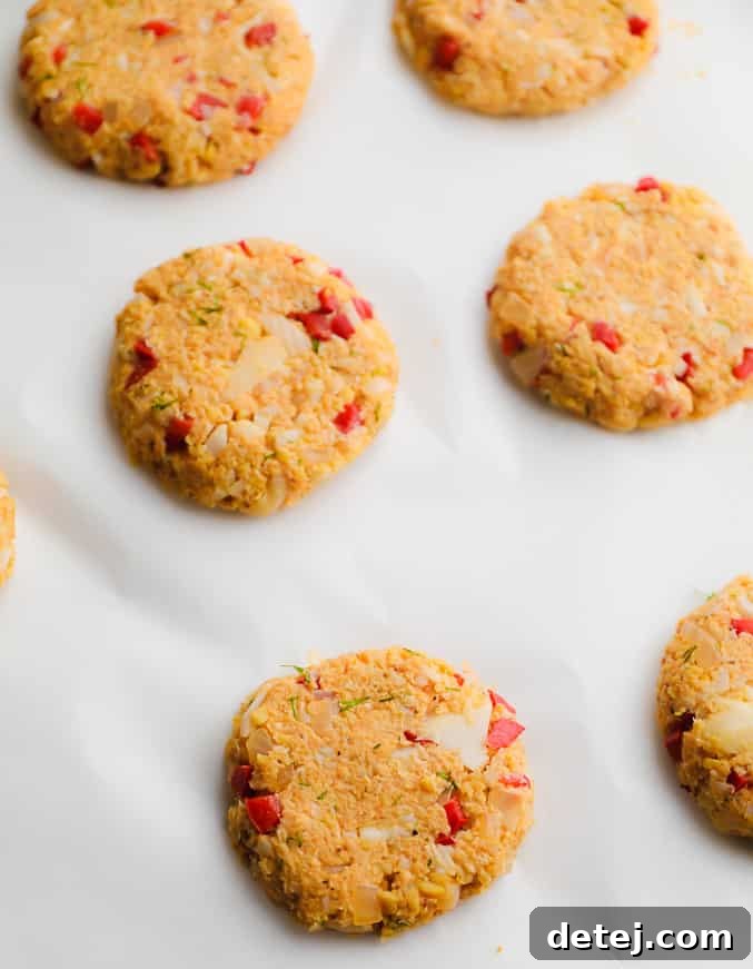 Round, golden-orange vegan crab cakes cooling on parchment paper after baking, ready to be served