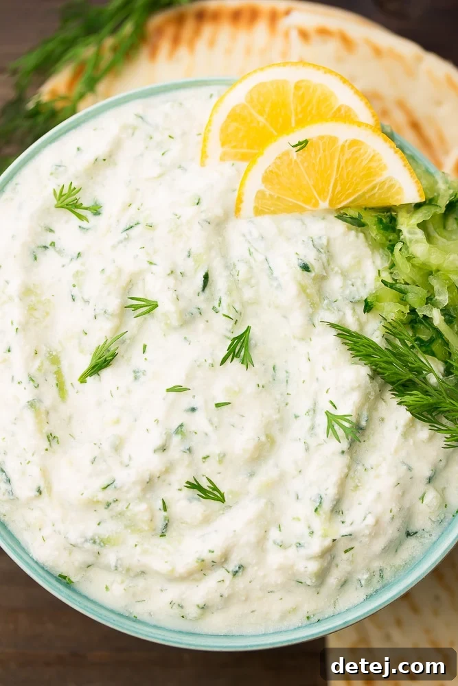 A beautifully presented bowl of creamy vegan tzatziki, garnished with fresh dill sprigs and bright lemon slices, ready for dipping.