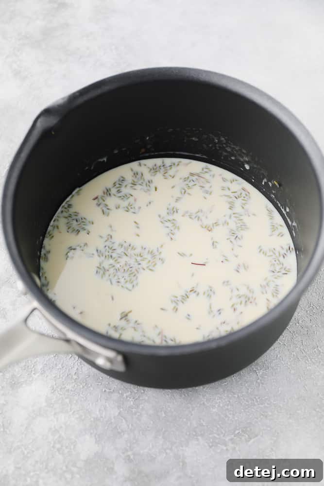 Dried culinary lavender steeping in warm non-dairy milk in a small saucepan on a kitchen stove, showing the infusion process.