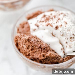 close up on a glass dessert cup holding chocolate mousse topped with whipped cream