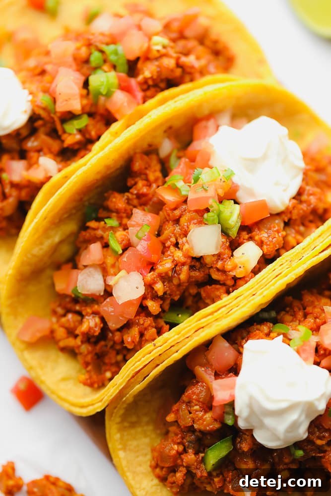 A close-up of three delicious corn tortilla tempeh tacos, garnished with fresh ingredients and ready to eat.