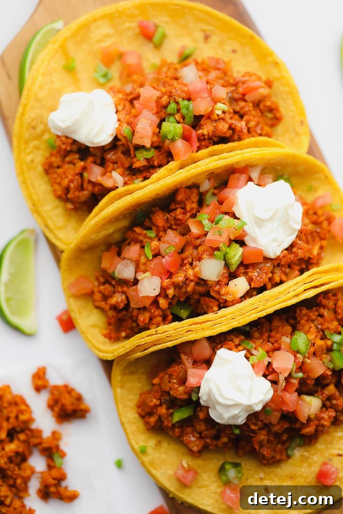 Three perfectly arranged corn tortilla tempeh tacos on a rustic wood serving platter, ready to be enjoyed.