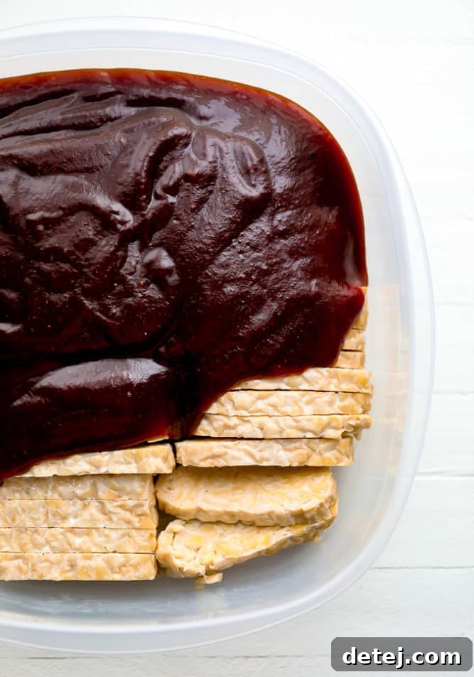 Tempeh marinating in BBQ sauce in a glass dish