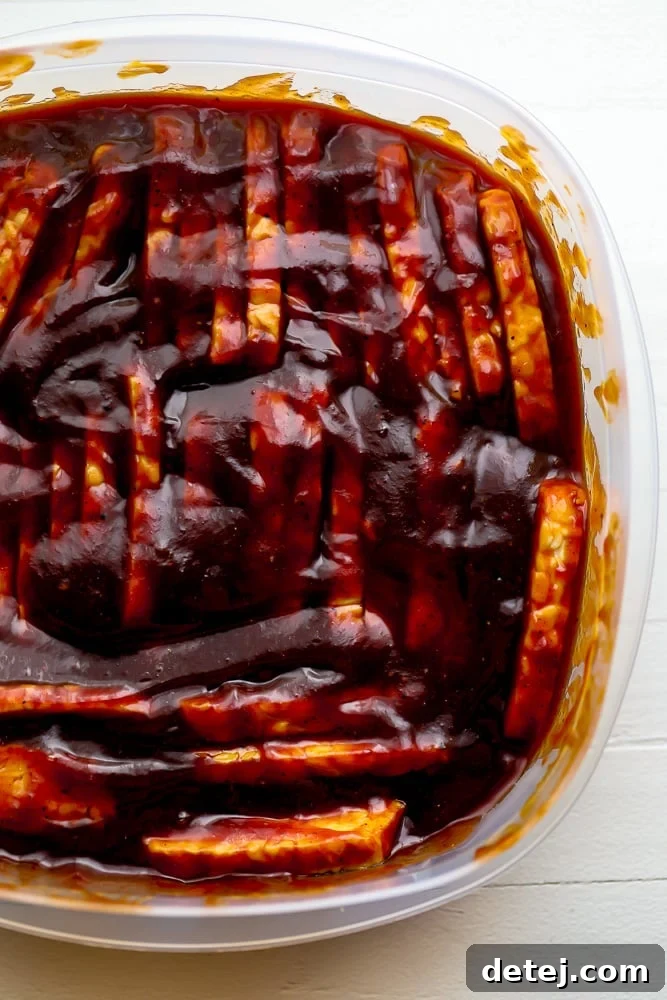 Marinating tempeh covered in BBQ sauce in a glass container