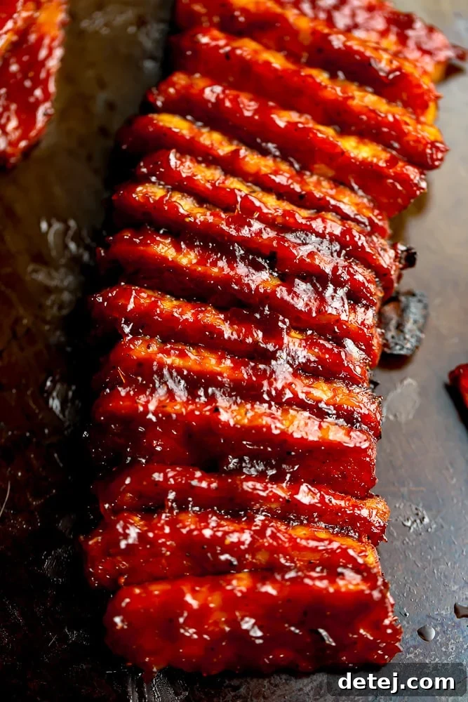 Many BBQ tempeh pieces laid out on a baking pan