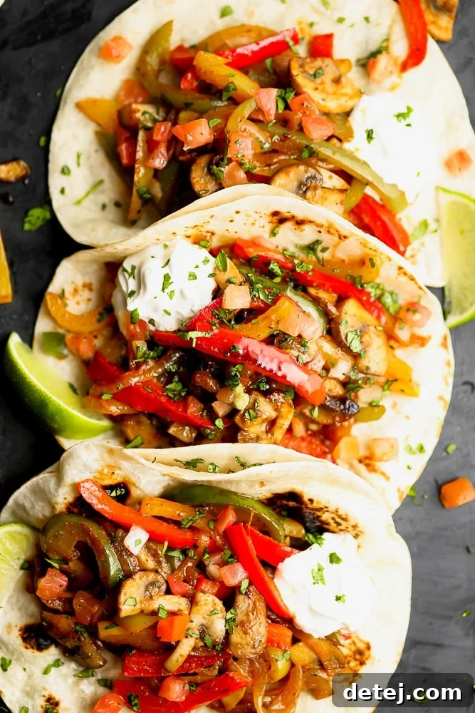 Three tortillas in a row, generously stuffed with colorful sauteed bell peppers, onions, and mushrooms for vegetarian fajitas, ready to be enjoyed.