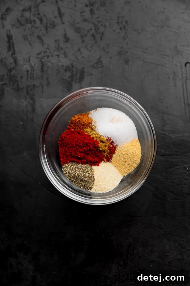 A small glass bowl containing a vibrant mixture of red, white, and beige seasonings, illustrating the homemade fajita spice blend.
