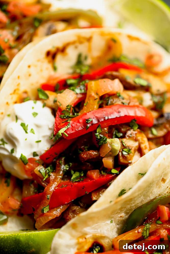 Plated vegetarian fajitas, neatly arranged in warm tortillas, served with a generous side of creamy vegan sour cream and fresh lime wedges.