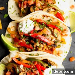 Three tortillas in a row, generously stuffed with colorful sauteed bell peppers, onions, and mushrooms for vegetarian fajitas.