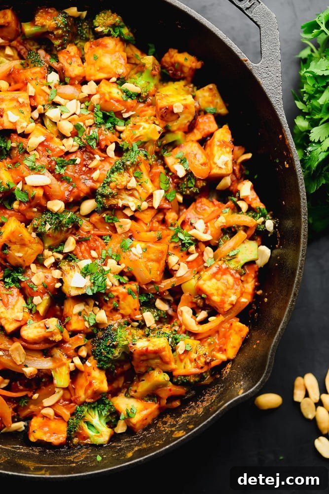 close up of orange stir fry with broccoli in a black skillet