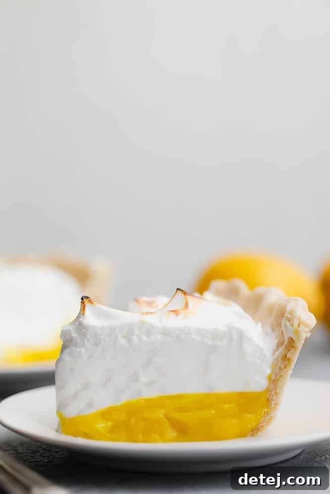 Fluffy Vegan Lemon Meringue Bliss 5 A perfect slice of Vegan Lemon Meringue Pie on a white plate, showcasing the distinct layers.