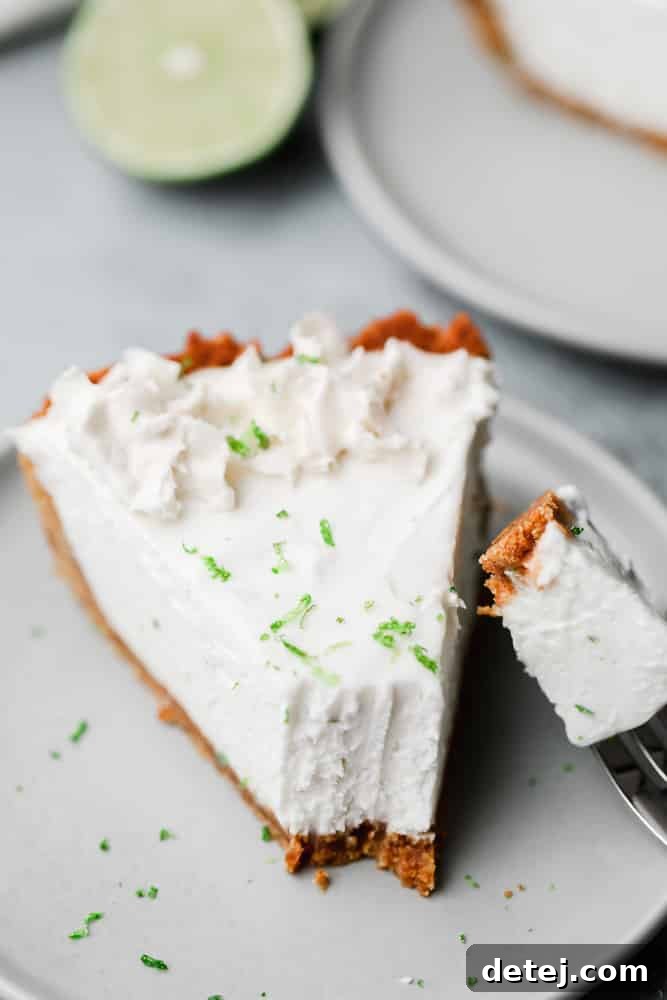 close up on a slice of white key lime pie with a fork taking a bite
