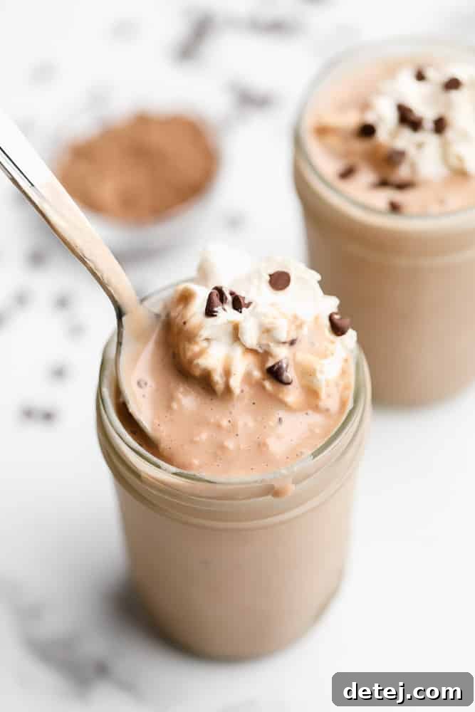 Plant-Based Power Shake 2 A spoon scooping a rich chocolate vegan protein shake from a mason jar, highlighting its thick, creamy texture, perfect for a satisfying breakfast.