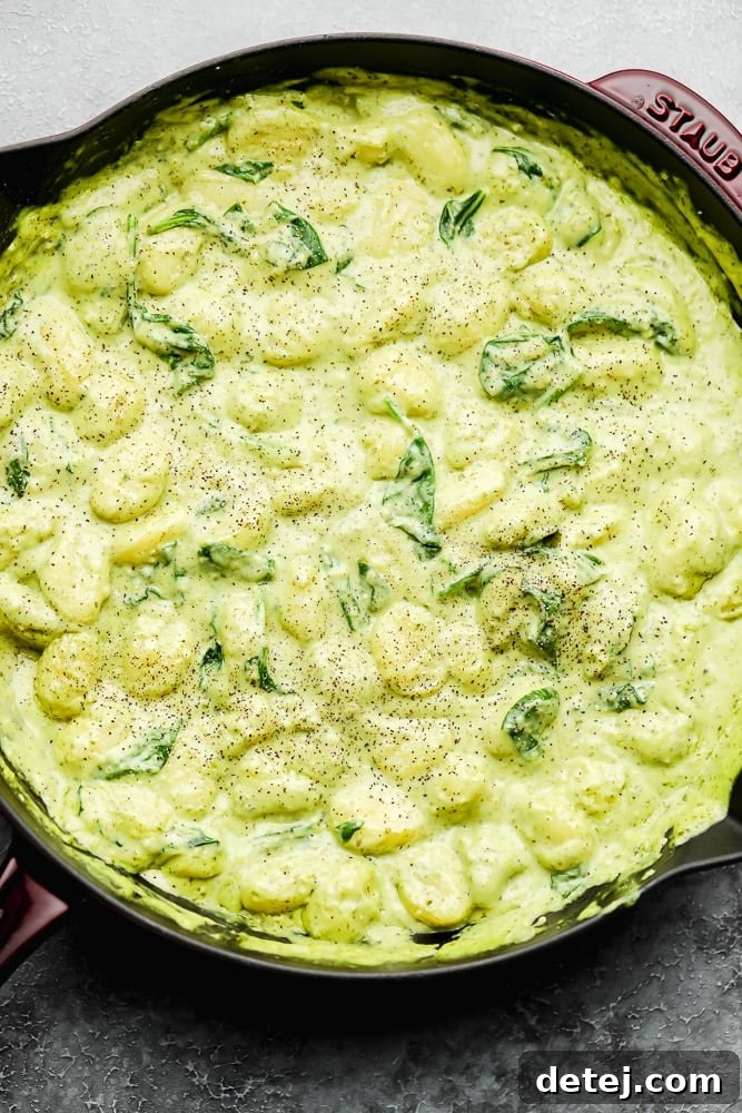 large pot filled with a green cream sauce and gnocchi
