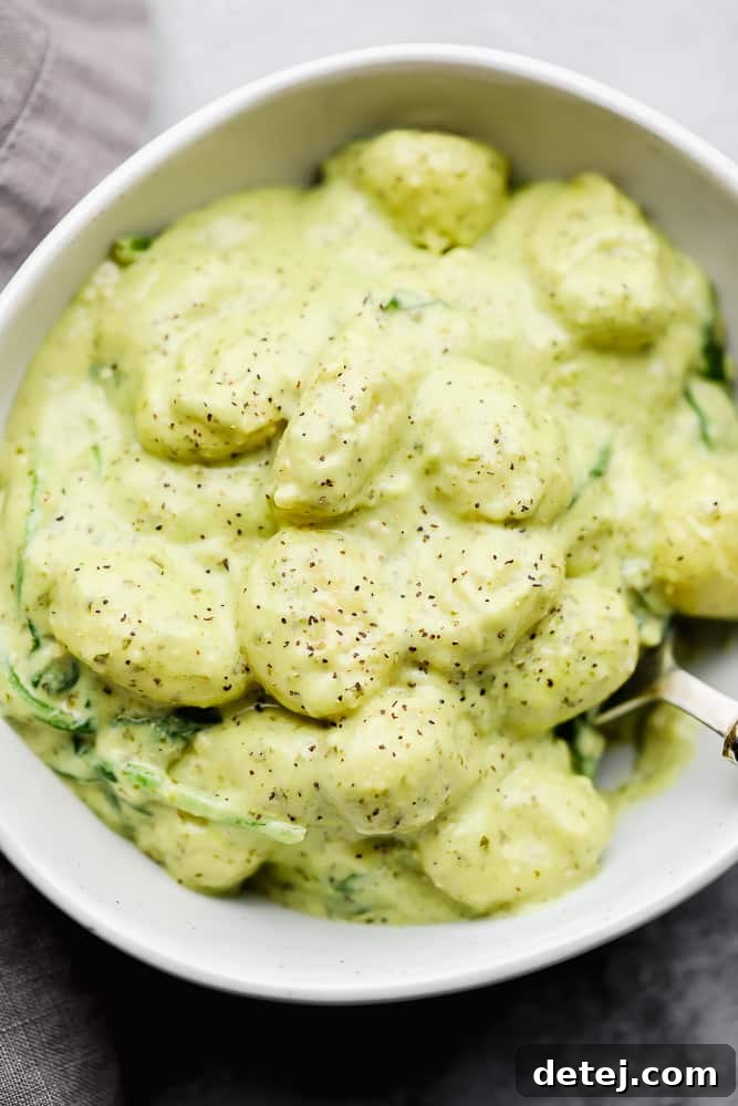 white bowl filled with gnocchi and a green creamy sauce