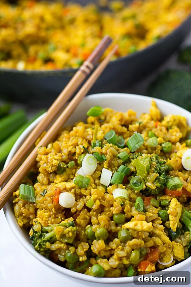 Golden Tofu Scramble Fried Rice 5 A side shot of a bowl of golden vegan fried rice, highlighting its fluffy texture and generous topping of scrambled tofu and green onions.