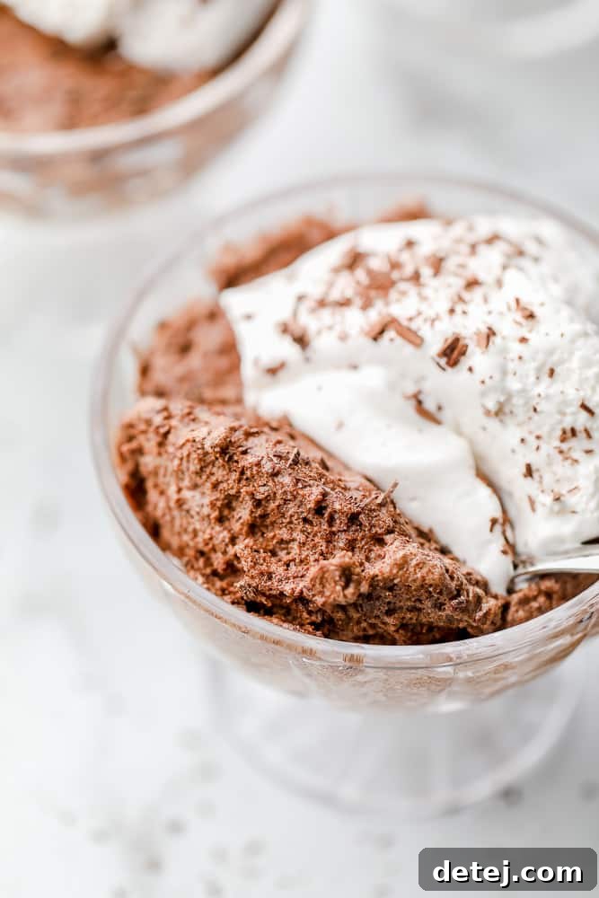Aquafaba Essentials 5 A elegant glass dessert cup filled with rich vegan chocolate mousse, topped with a swirl of vegan whipped cream, highlighting the luxurious textures achievable with aquafaba.