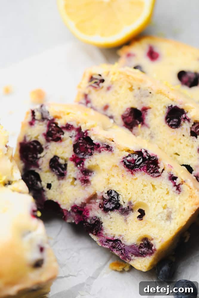 close up on 3 slices of blueberry and lemon bread, showcasing its moist texture and vibrant blueberries