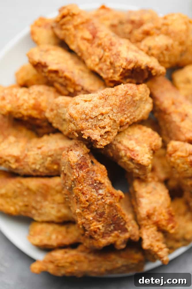Another close-up shot of a large plate brimming with golden brown, perfectly fried vegan chicken pieces, ready to be served and enjoyed.