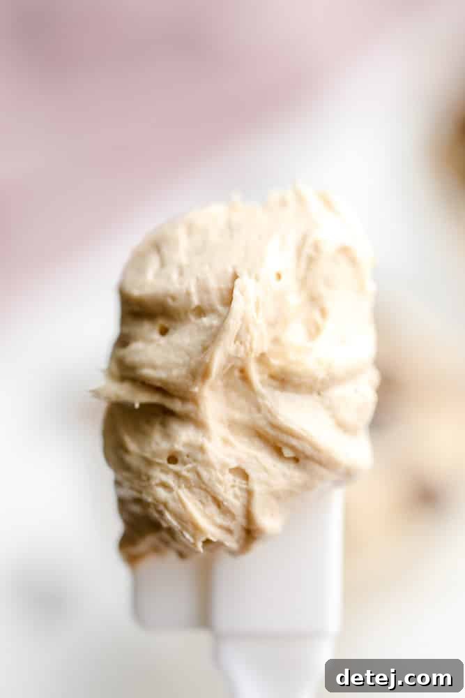 close up on a white spatula holding a scoop of beige peanut butter mousse
