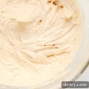 close up on a glass bowl filled with a beige, creamy peanut butter mousse