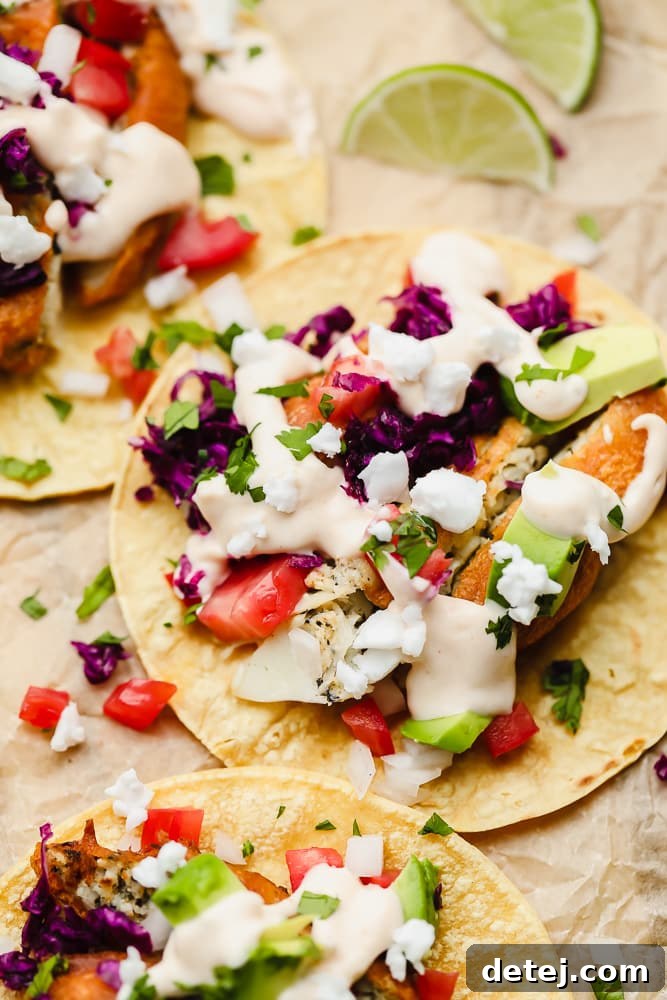 Close-up of a perfectly assembled vegan fish taco on a corn tortilla, adorned with purple cabbage and a luscious white sauce, resting on parchment paper.