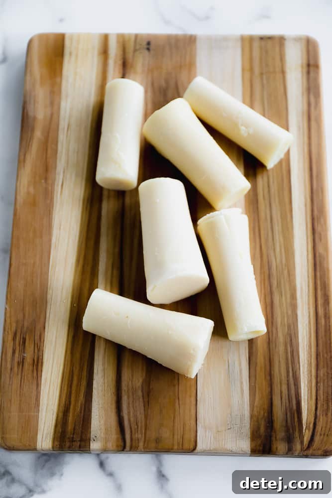 White hearts of palm stalks arranged neatly on a rustic wooden cutting board, ready for slicing.