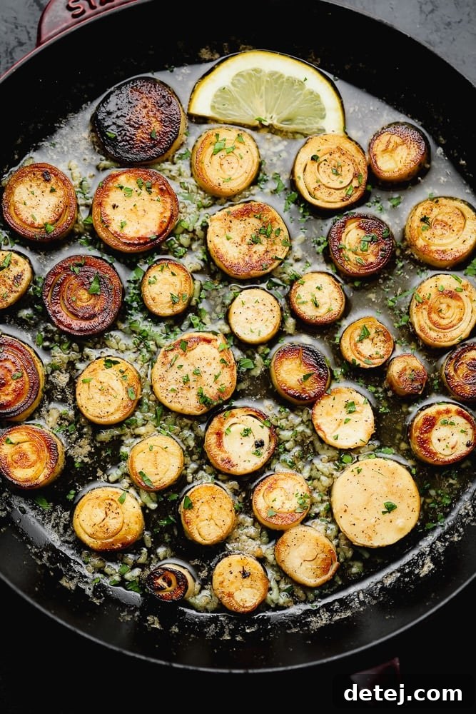 Golden-brown vegan scallops sizzling and browning in a large black non-stick skillet.
